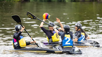 Four players are on the field. One woman (yellow team) is ready to throw the ball