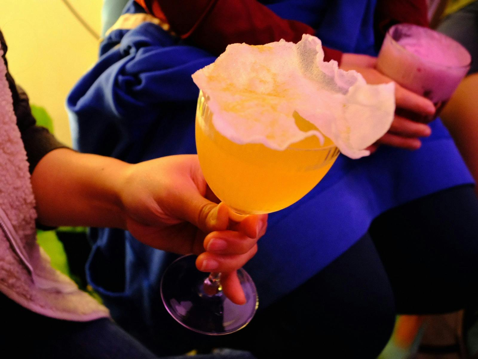 hand holding a drink with rice puff garnish