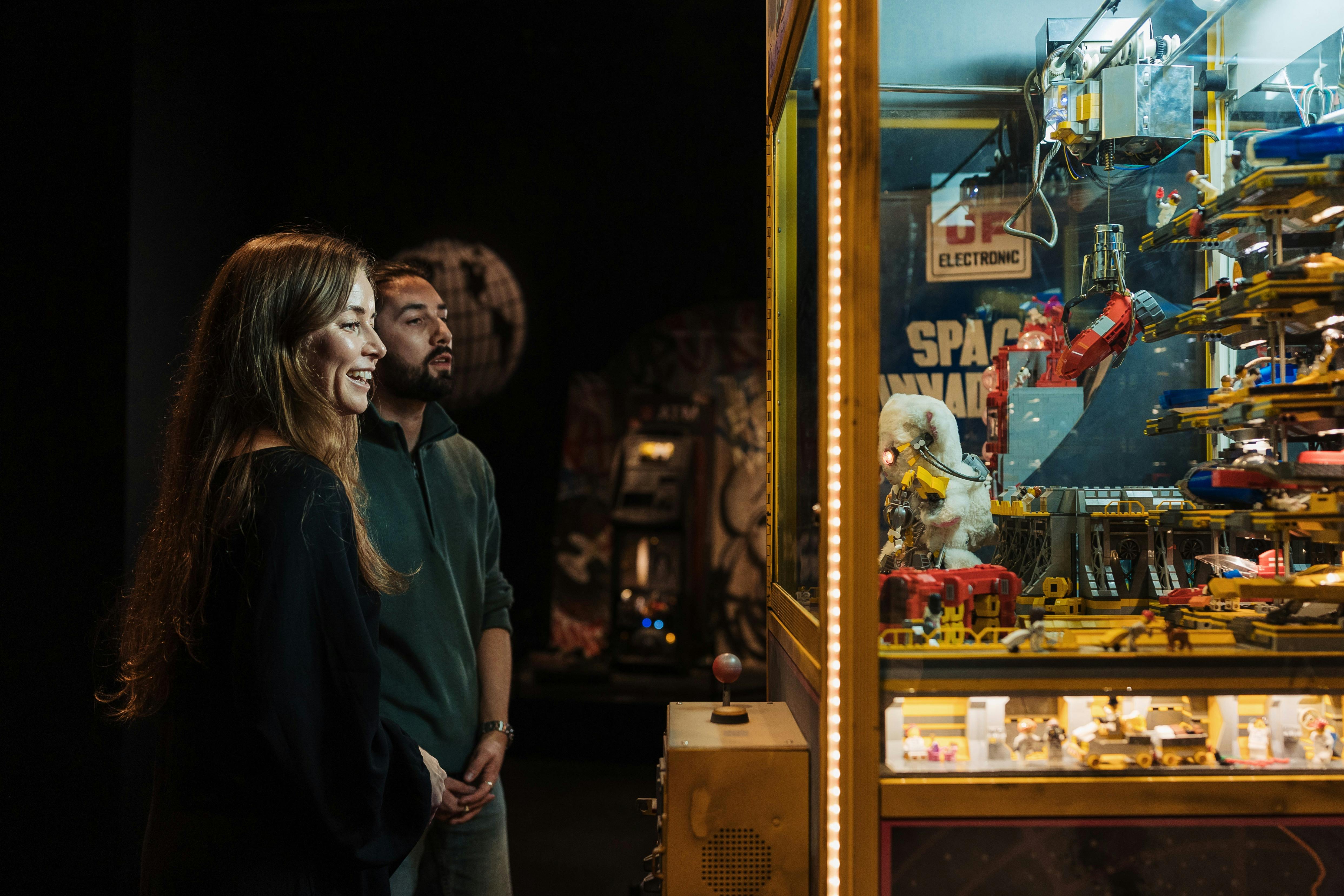 Adult couple enjoying observing a claw machine exhibit in RELICS