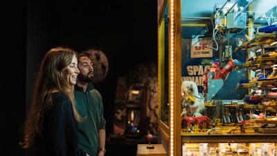 Adult couple enjoying observing a claw machine exhibit in RELICS