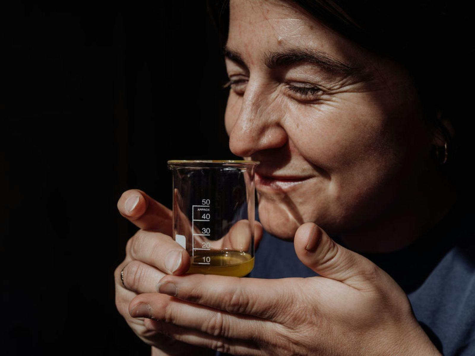 A woman smells a Tasmanian perfume held in a beaker