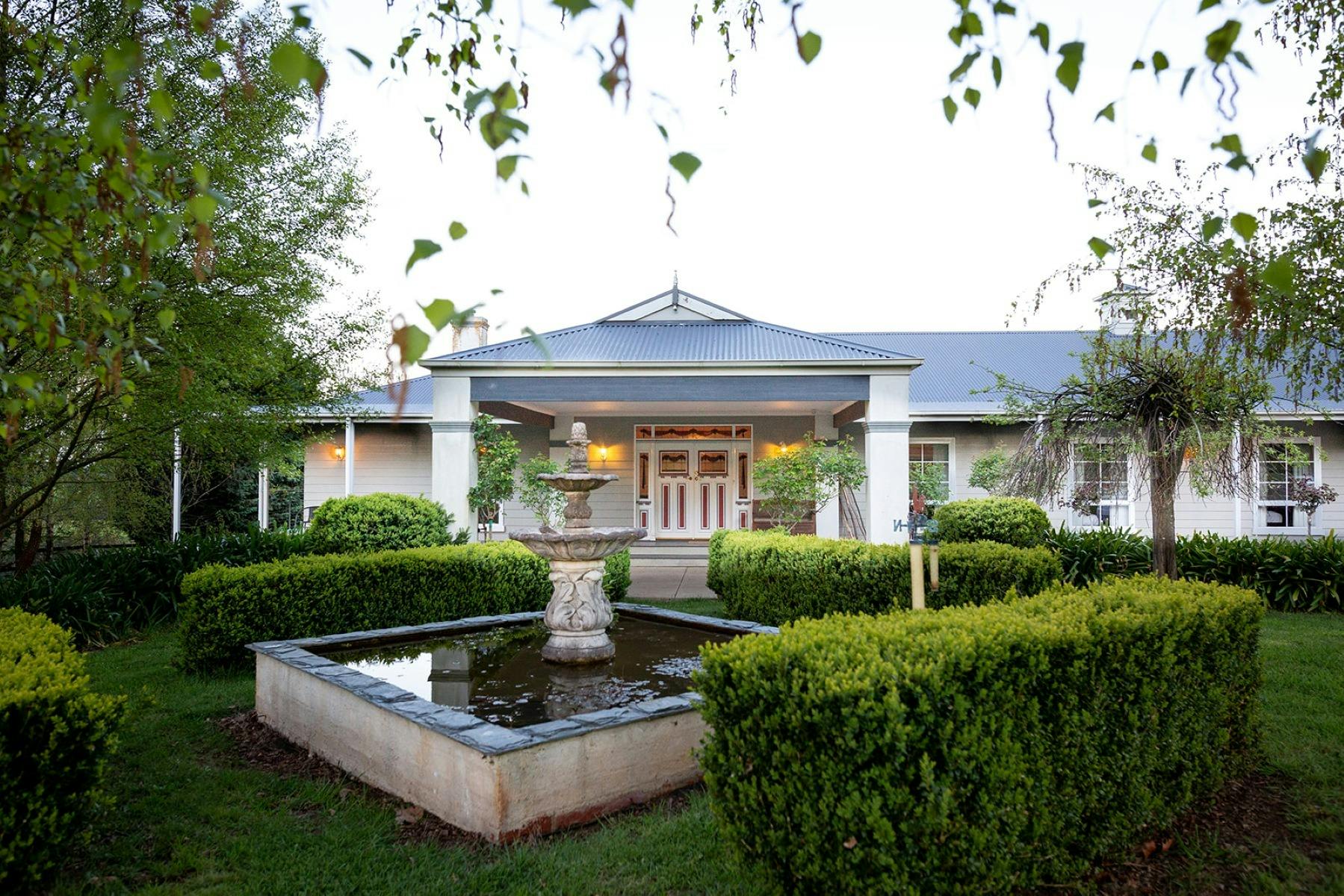 The front of a house with a water fountain in the foreground