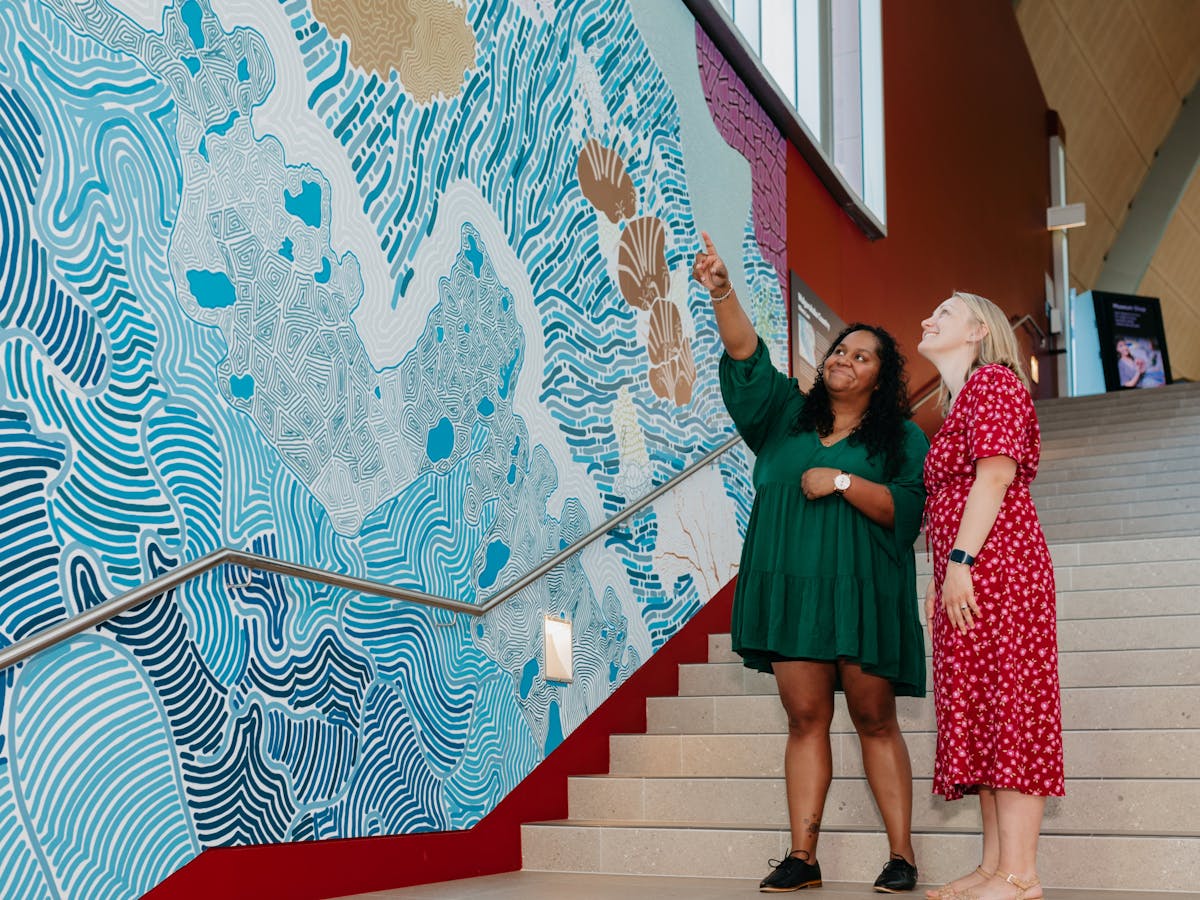 2 women looking at an indigenous mural