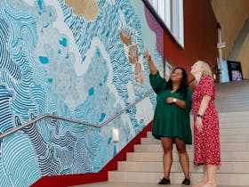 2 women looking at an indigenous mural