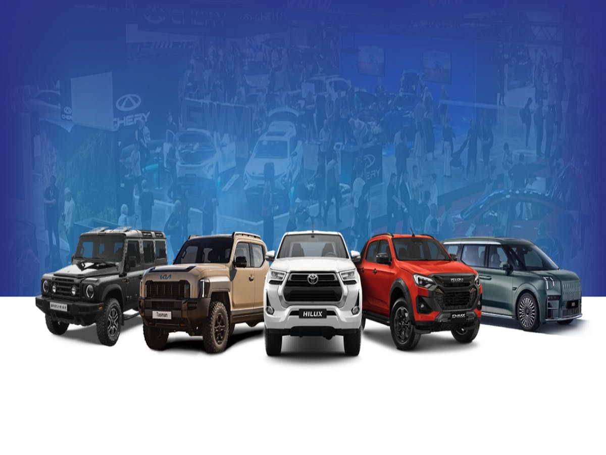 Lineup of five light commercial vehicles including utes, SUVs, and a van at a motor show.