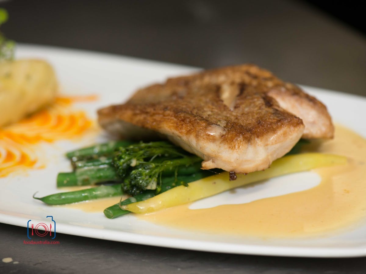 Locally sourced fish on white plate with green beans and sauce