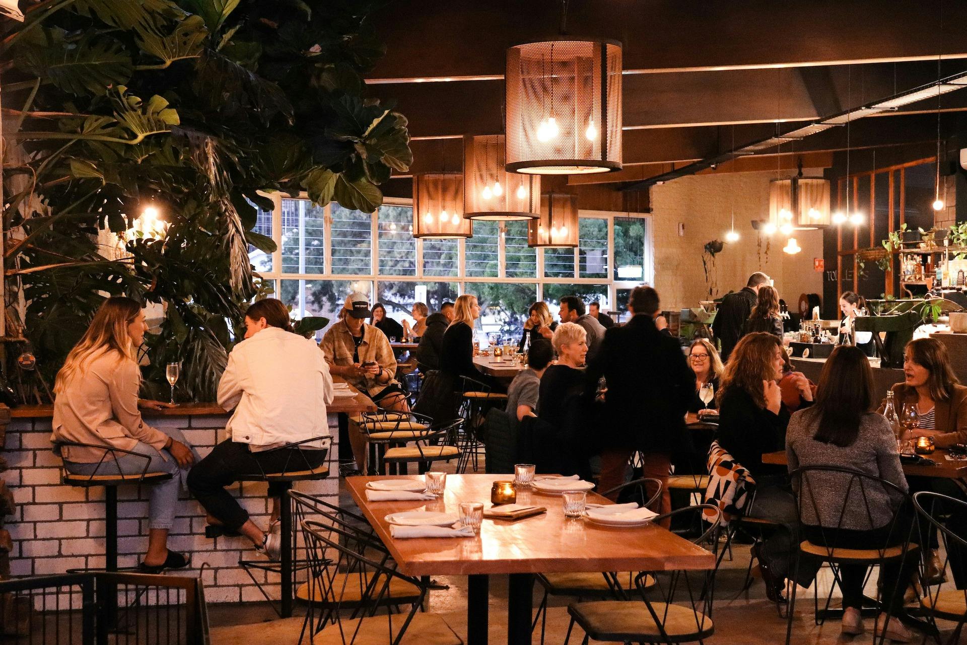 Photo showing people dinning inside the restaurant a mix of low and high tables
