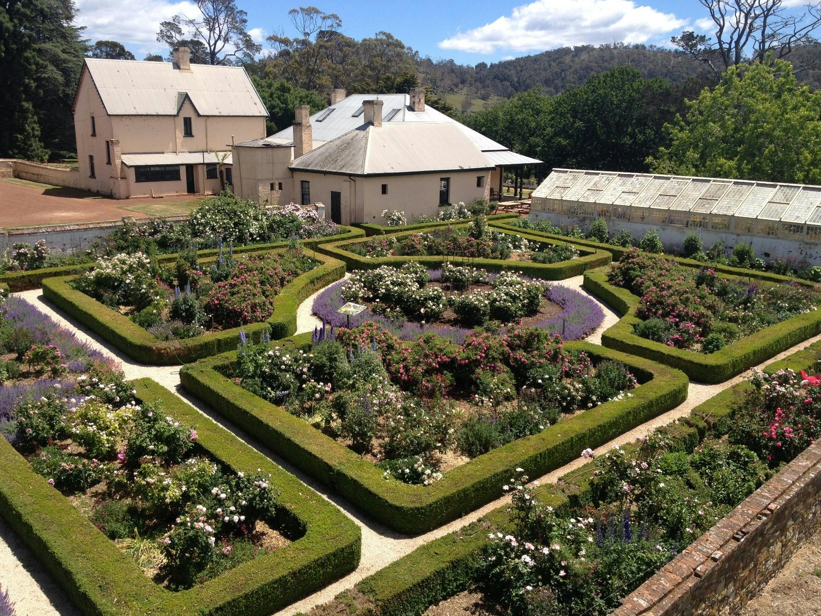 Large walled garden with neatly maintained hedges and various rosebushes