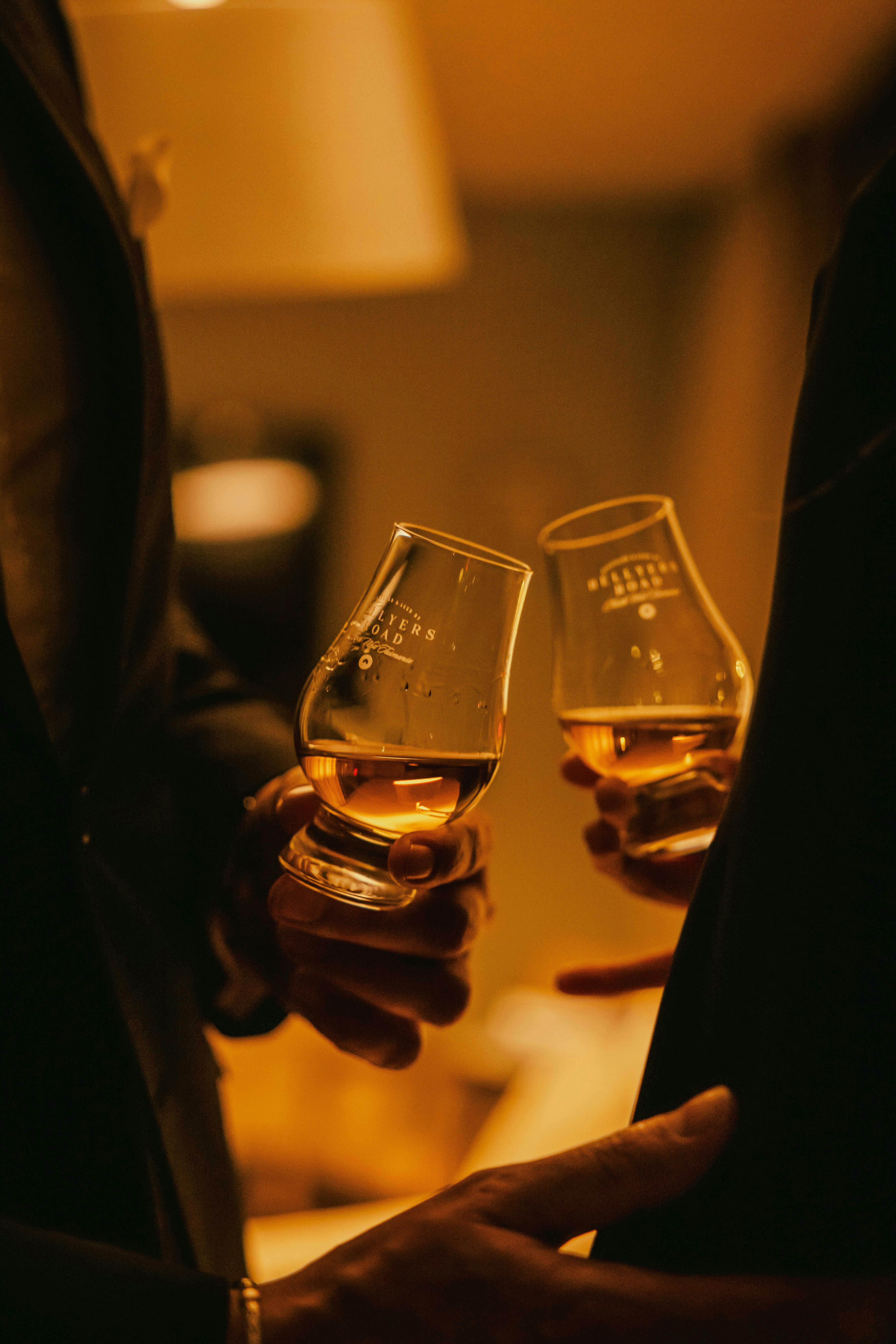 Two glasses of whisky being shared between two people in shadow