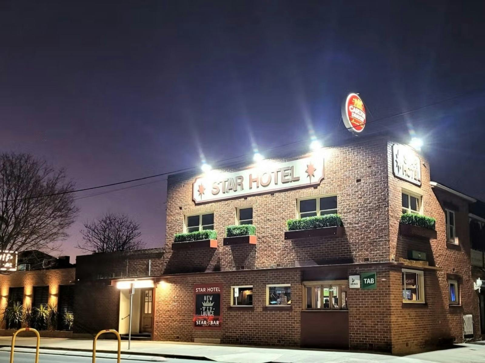 Photo of red brick hotel with lights on and purple sky in the background