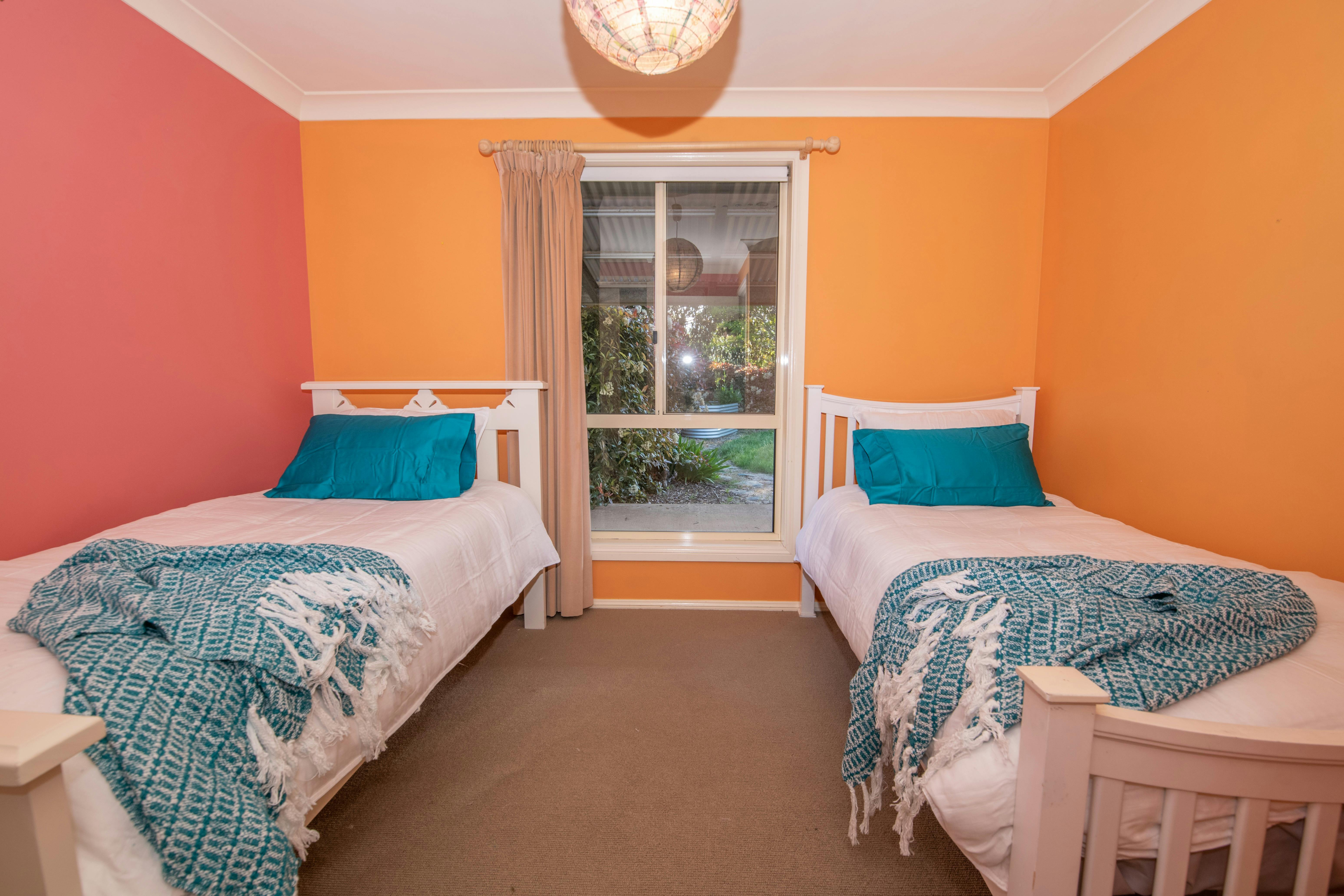 View of the twin beds in the third bedroom including a garden-facing window.