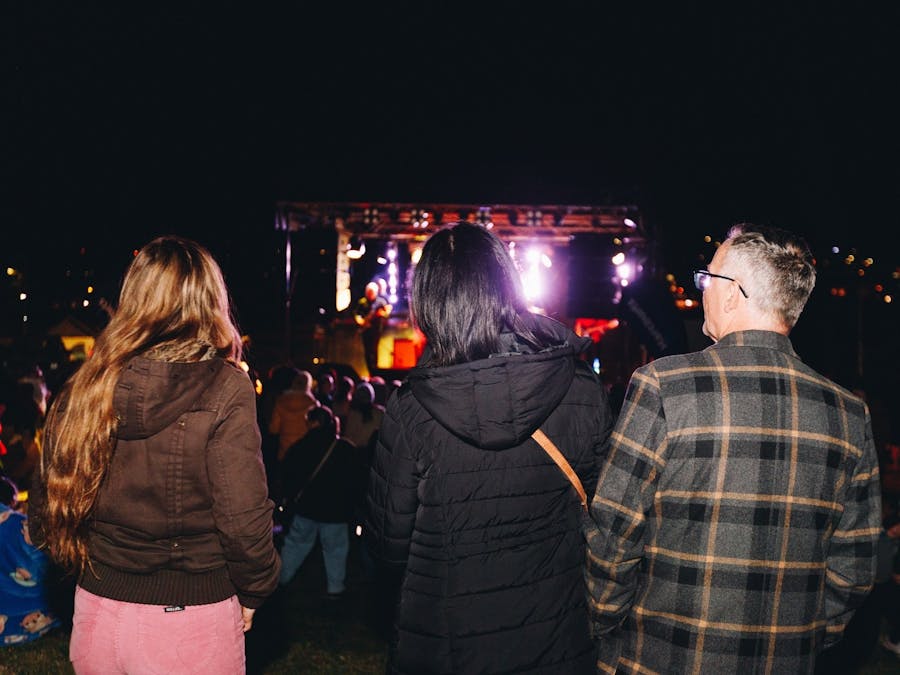 Three people watching band perform on stage