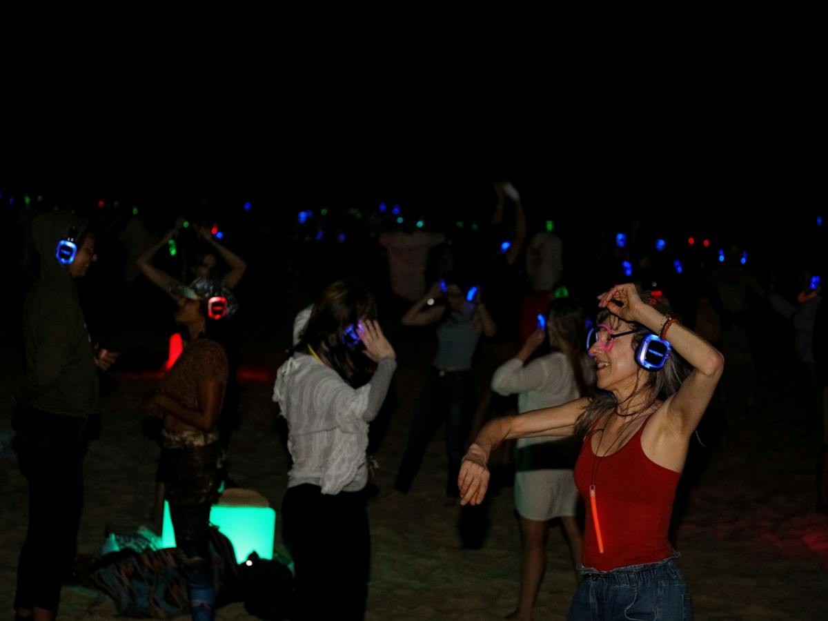 People dancing on the beach at Silent Disco Under the Stars at the 2024 SWELL Sculpture Festival