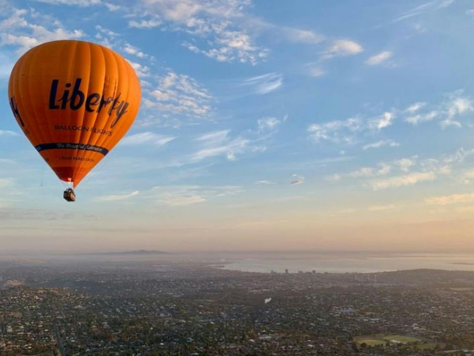 Hot air balloon floating over Geelong where the land meets the ocean