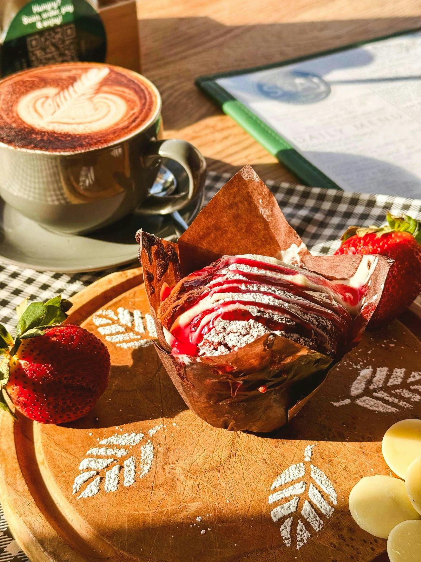 Strawberry drizzle on muffin, a strawberry and coffee.