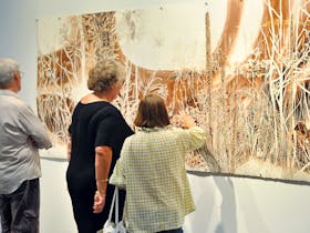 Visitors examine an artwork at Hervey Bay Regional Gallery