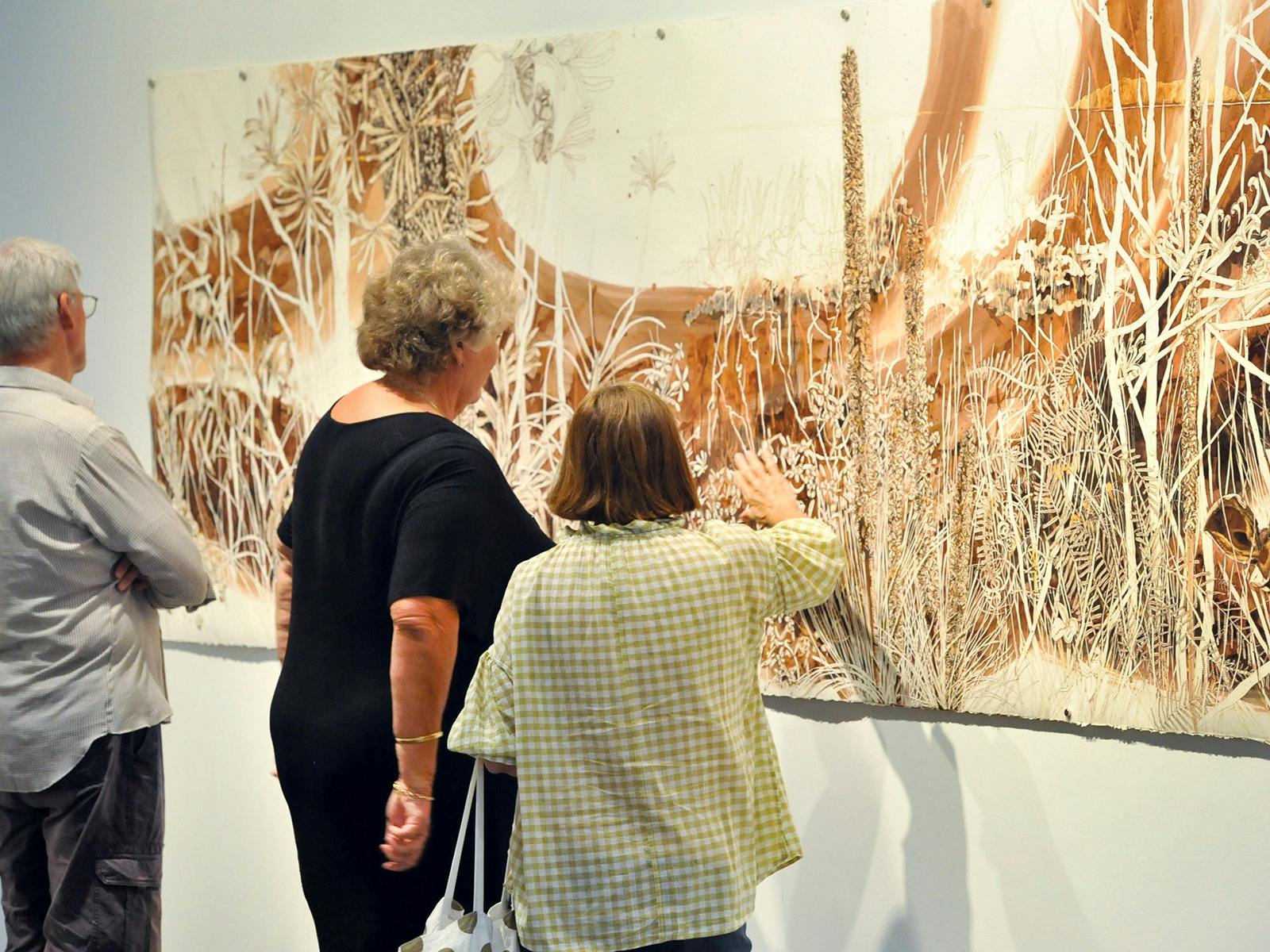 Visitors examine an artwork at Hervey Bay Regional Gallery
