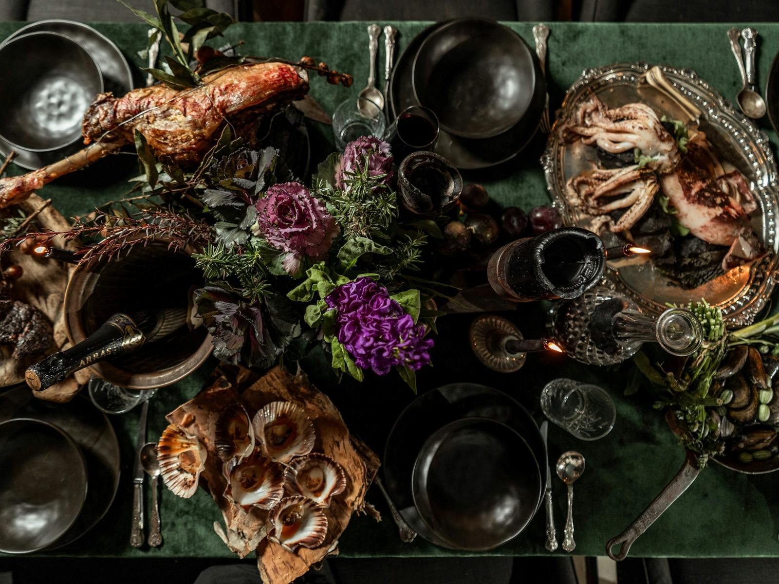 Overhead Earth Walker feast of fire-cooked meats, seafood, seasonal produce, flowers, and rustic war