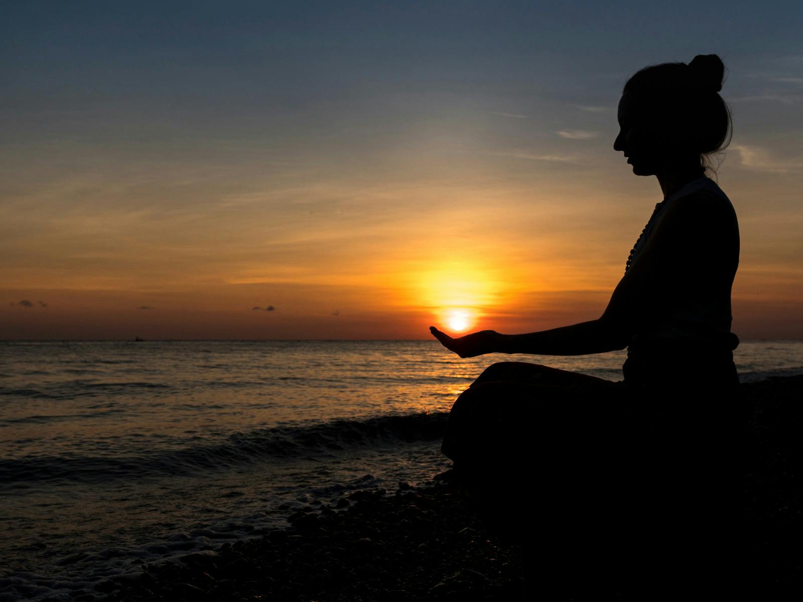 Woman sitting by the beach at sunset