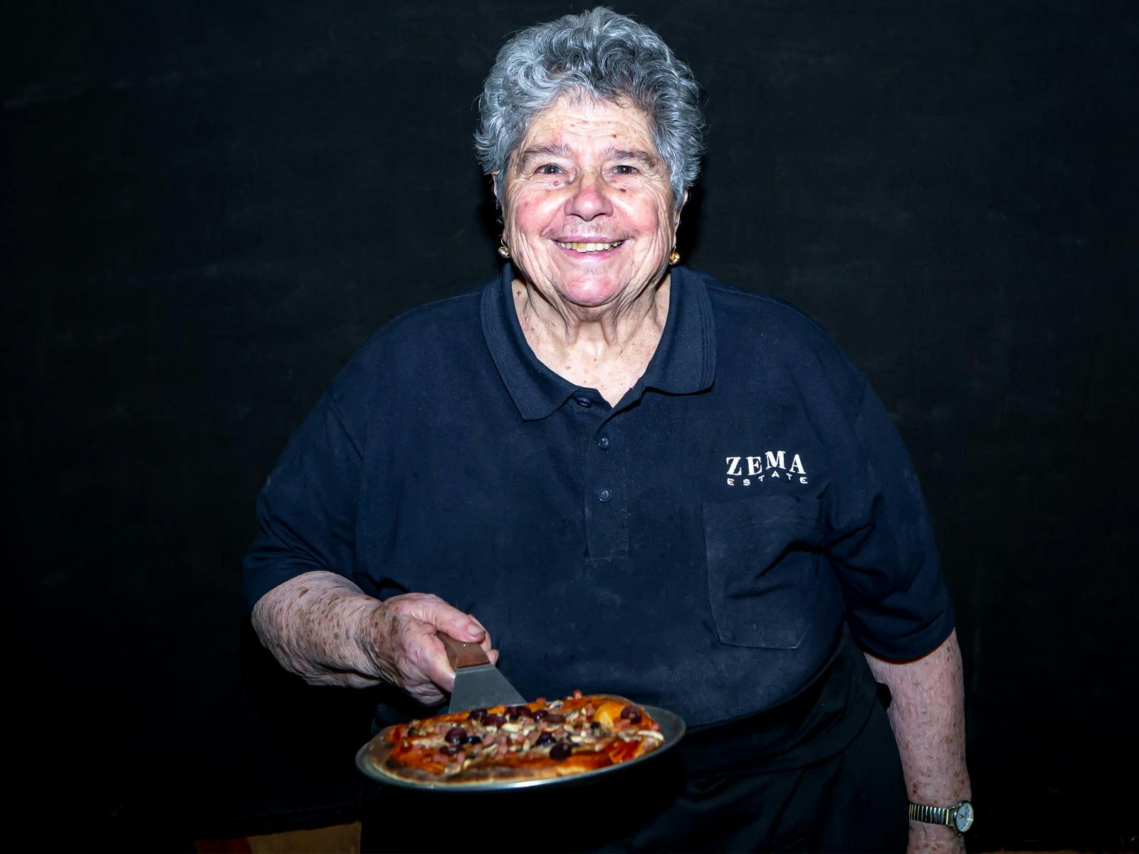 Mrs Zema holds pizza at Zema Estate event