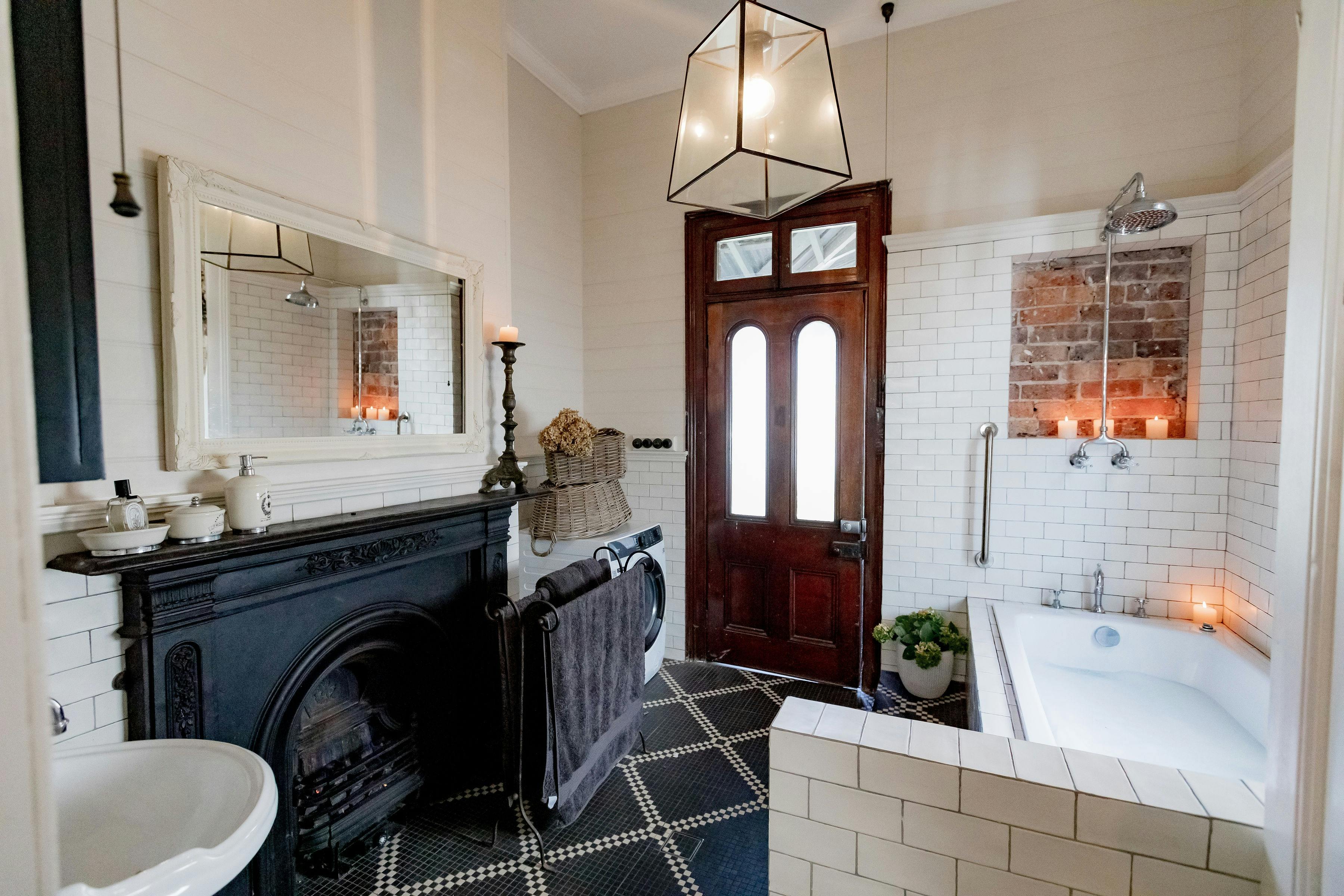 Black tiled bathroom with an open fire, running bath and toilet