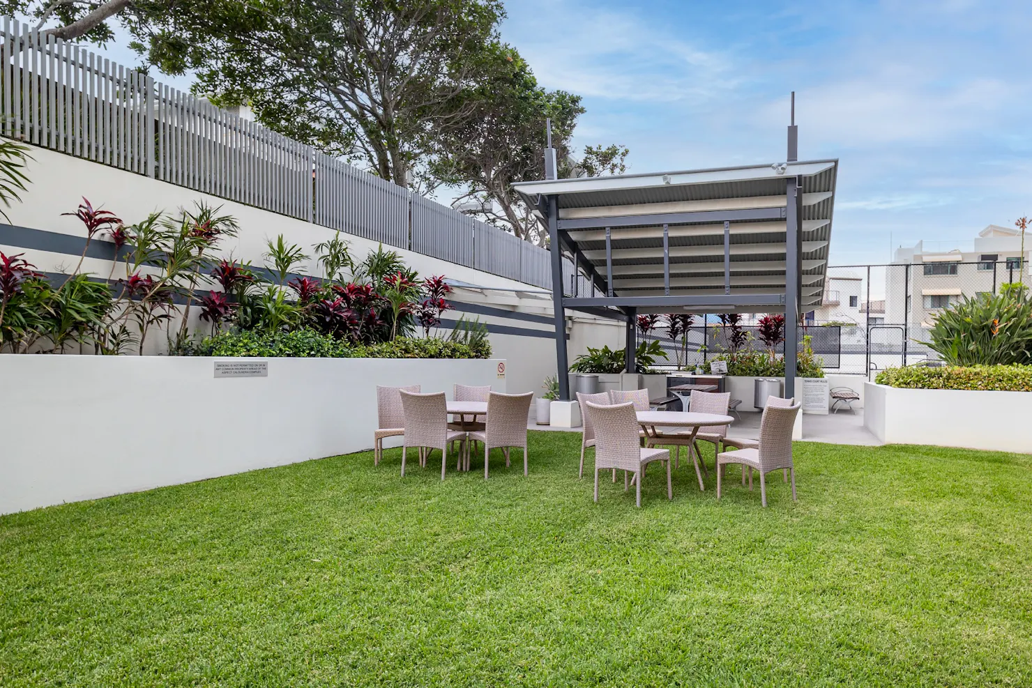 Poolside grassed area with seating and bbq