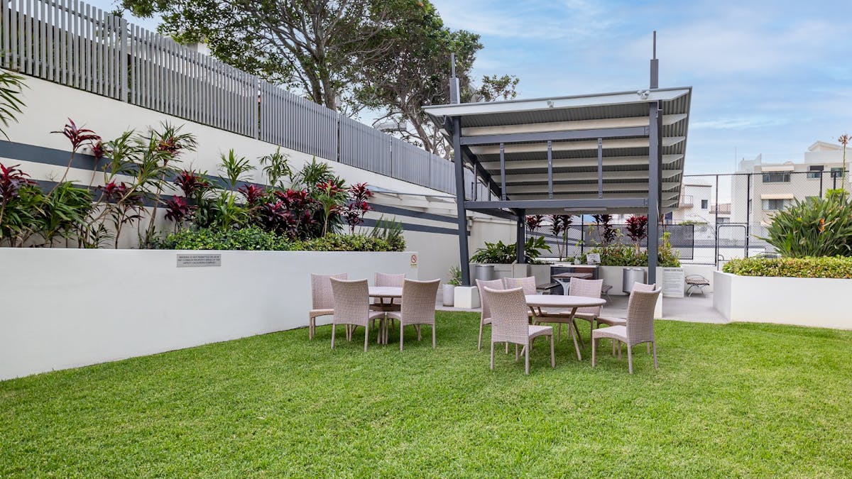 Poolside grassed area with seating and bbq