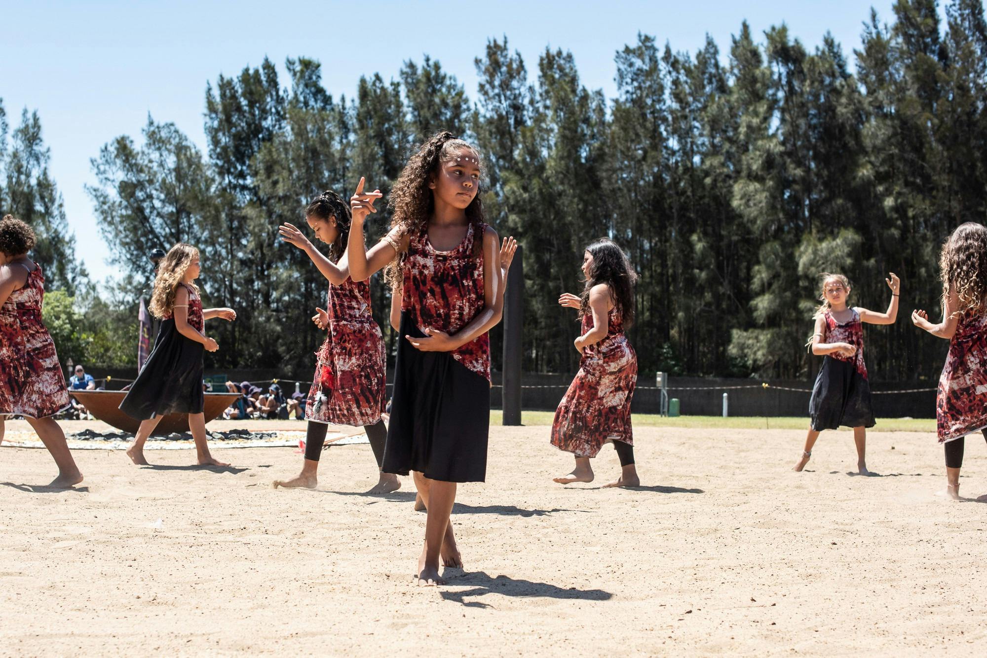 Multiple First Nations dances performing outdoors on the dance ground.