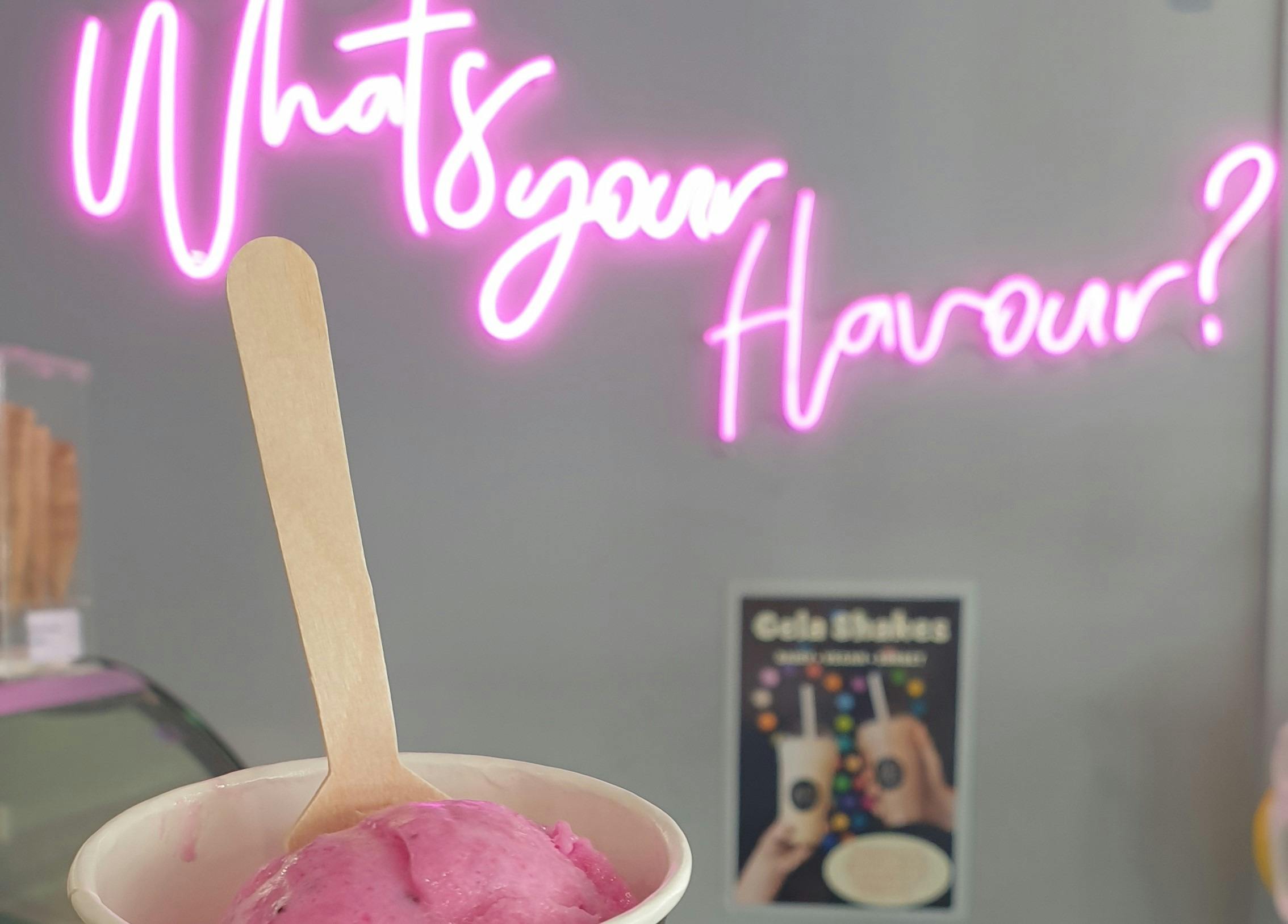 A neon sign says 'What's your flavour?' with pink ice-cream just visible at the bottom.