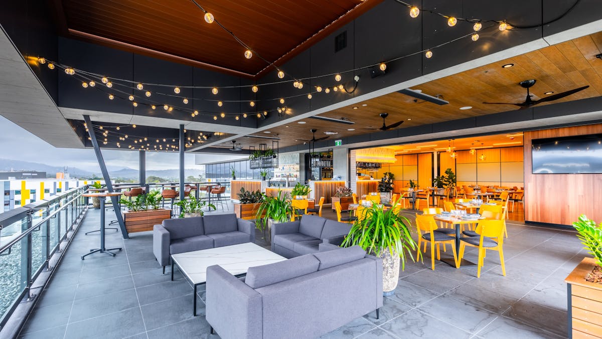 Rooftop area with lounges and tables, festoon lights and hinterland views