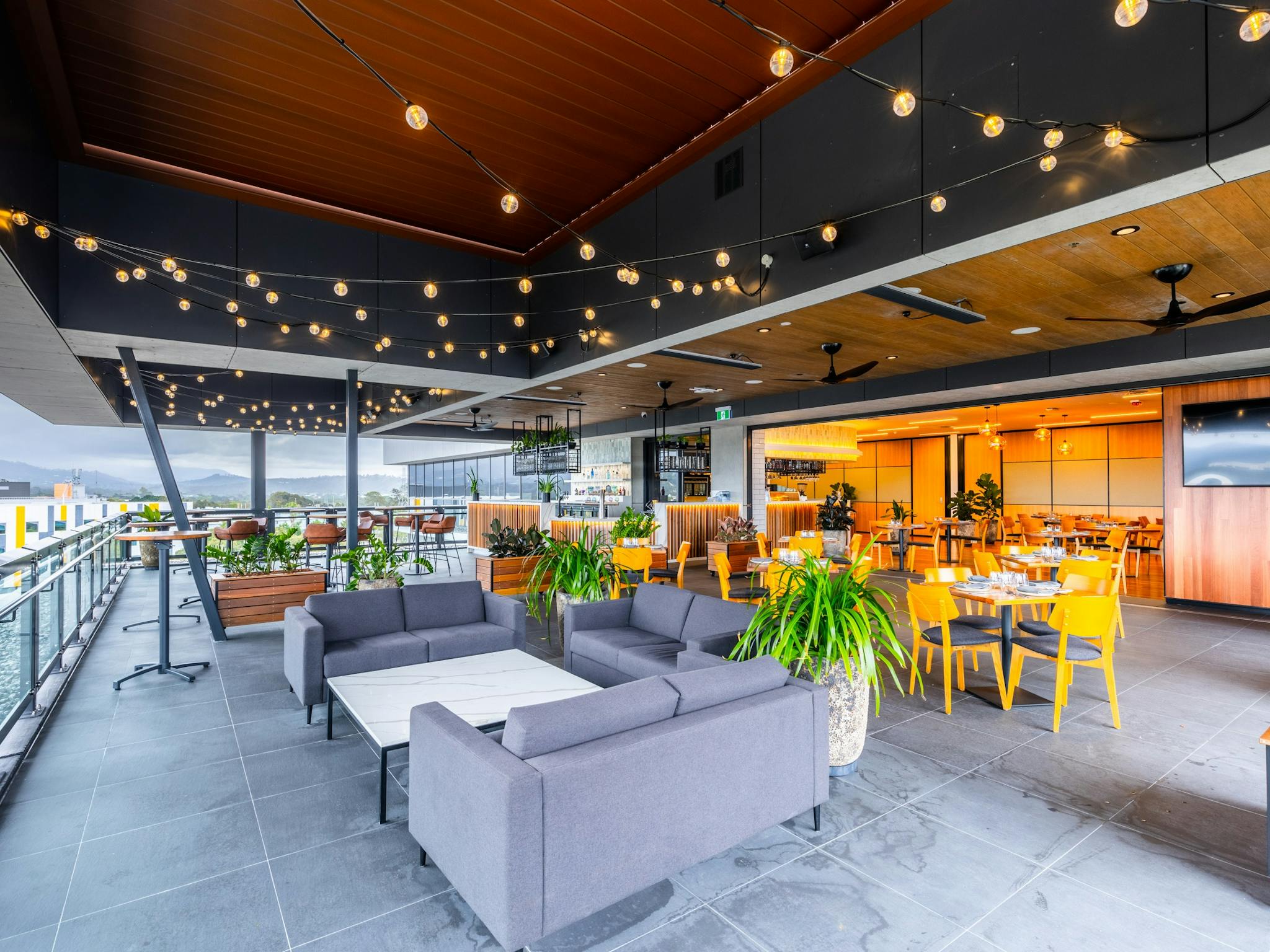 Rooftop area with lounges and tables, festoon lights and hinterland views Rooftop area with lounges and tables, festoon lights and hinterland views