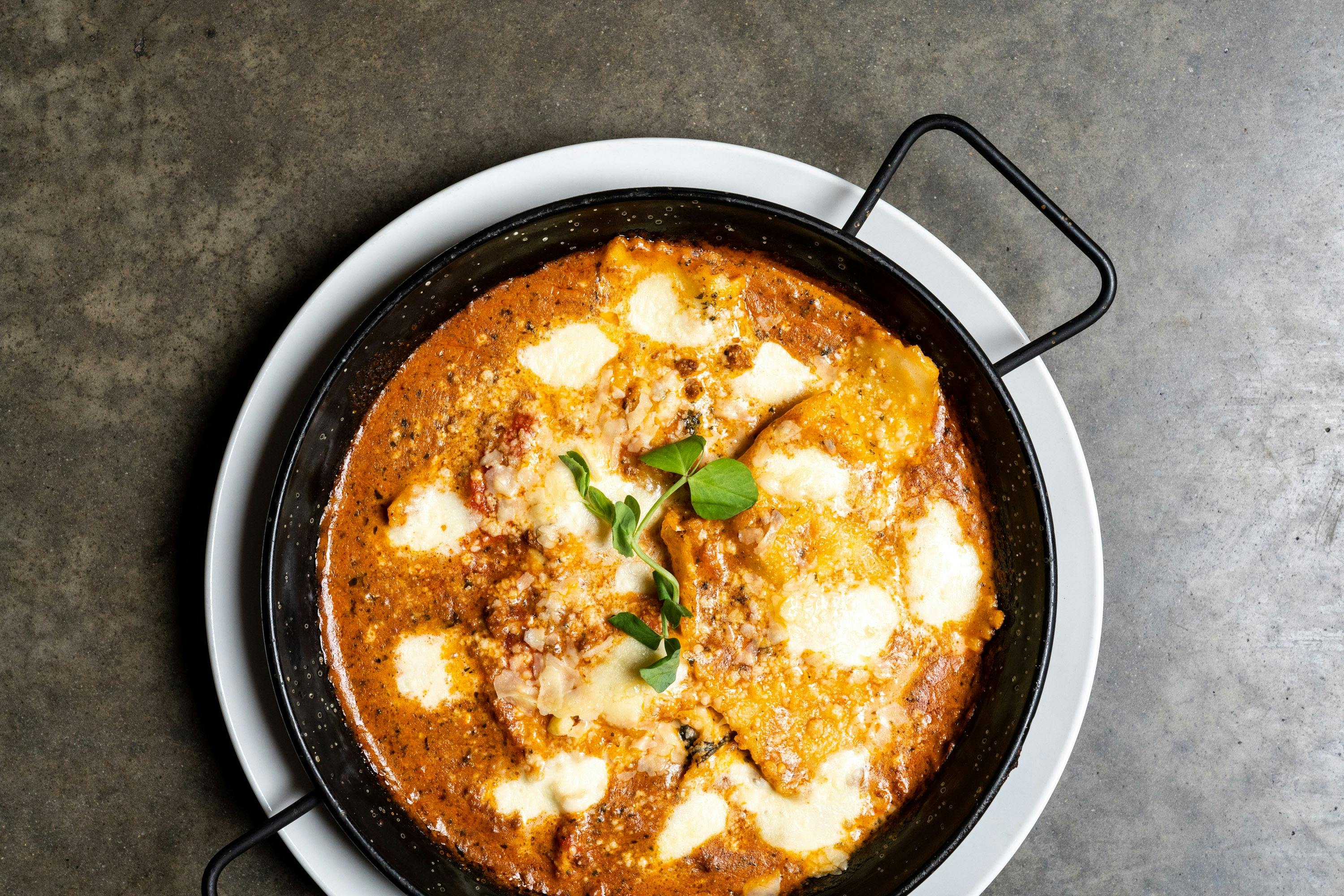 A black plate of Baked Ravioli Milanese