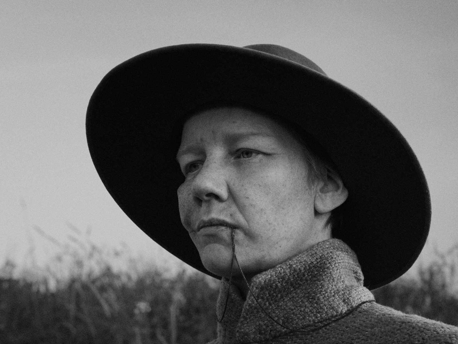 A woman in black and white stares solemnly