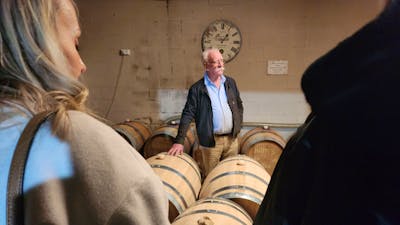 A man standing in front of a group of wooden barrels.