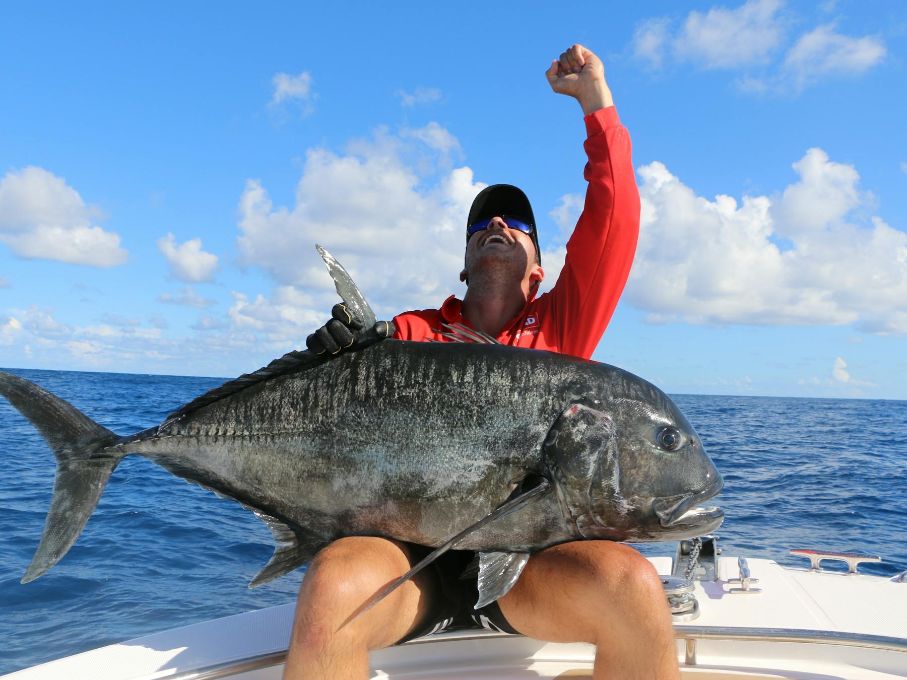 photo showing a man sitting on a small boat with a large GT on his lap