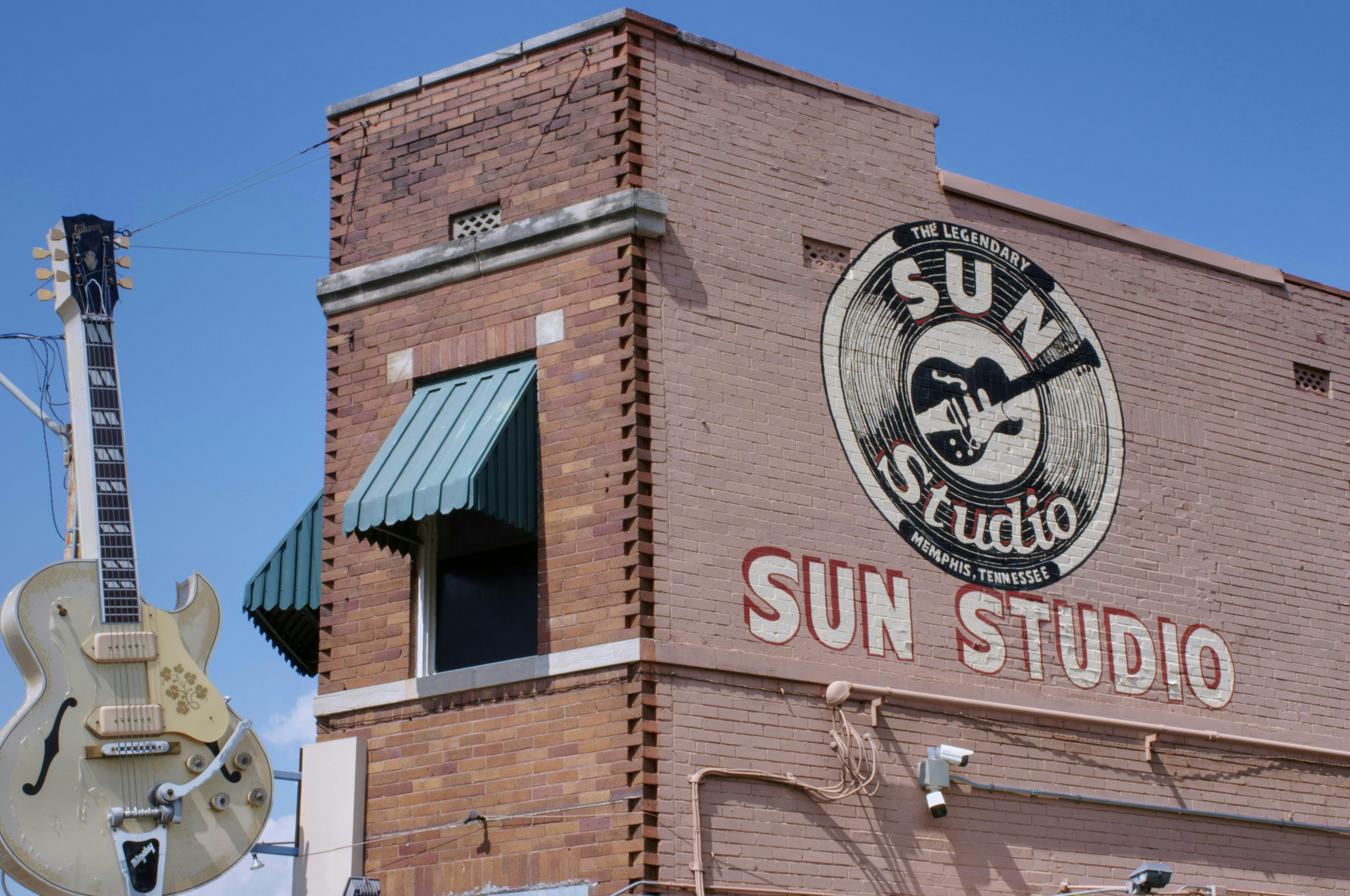A red brick building with the Sun Studio Record label printed on the side with a large guitar statue