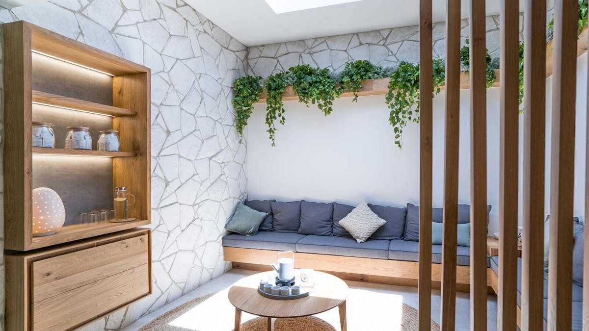 Bench seating with stone wall, skylight and wooden console with tea station and lamp