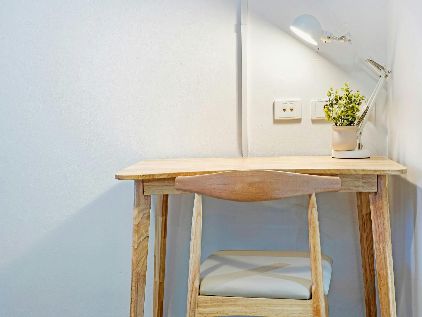 Compact wooden work desk with lamp and decorative plant.