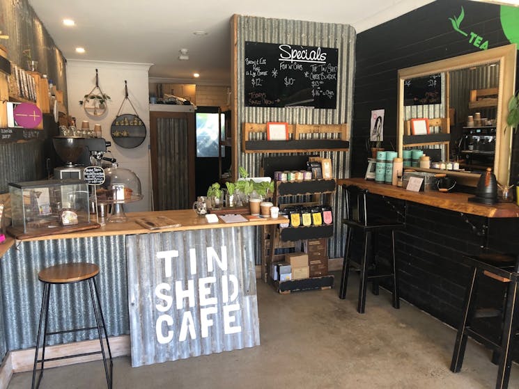 Timber bench tops and corrugated iron walls with mirrors and logos painted on walls with coffee