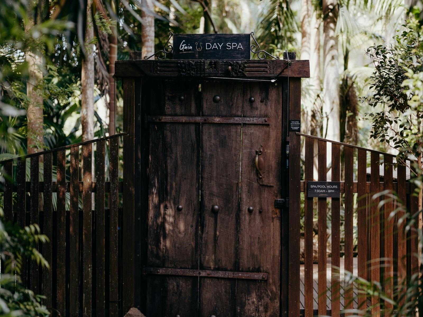 large timber door leading to spa. overhanging trees from lush garden