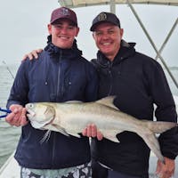 Men holding salmon catch with Gone Fishing Cairns on the calm Trinity Inlet
