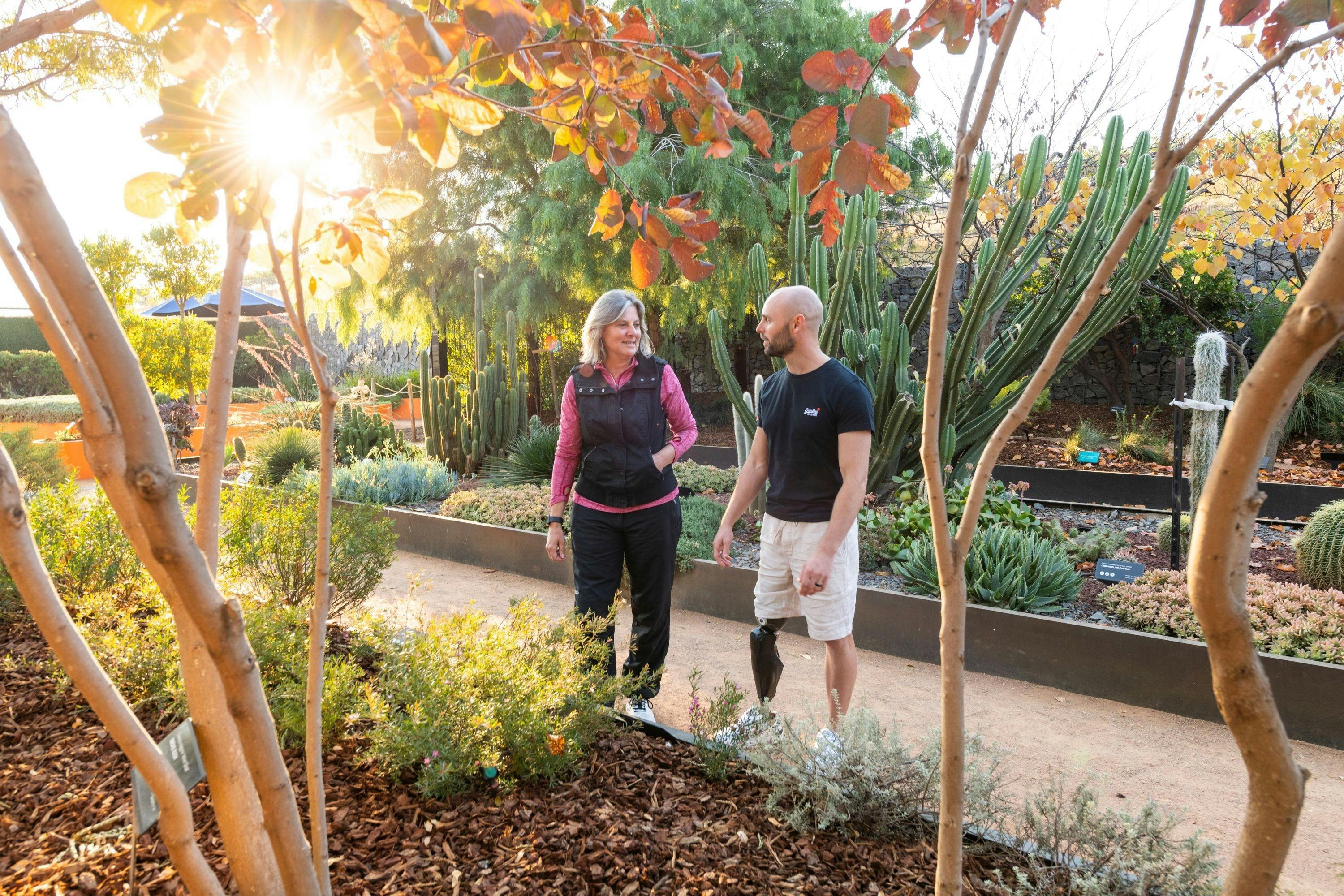 Two people in a garden with autumn leaves and cacti