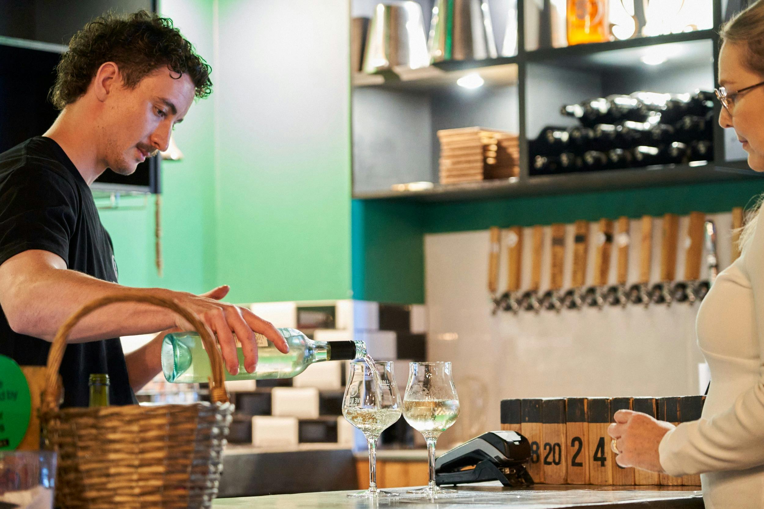 Staff member pouring a glass of locally produced white wine