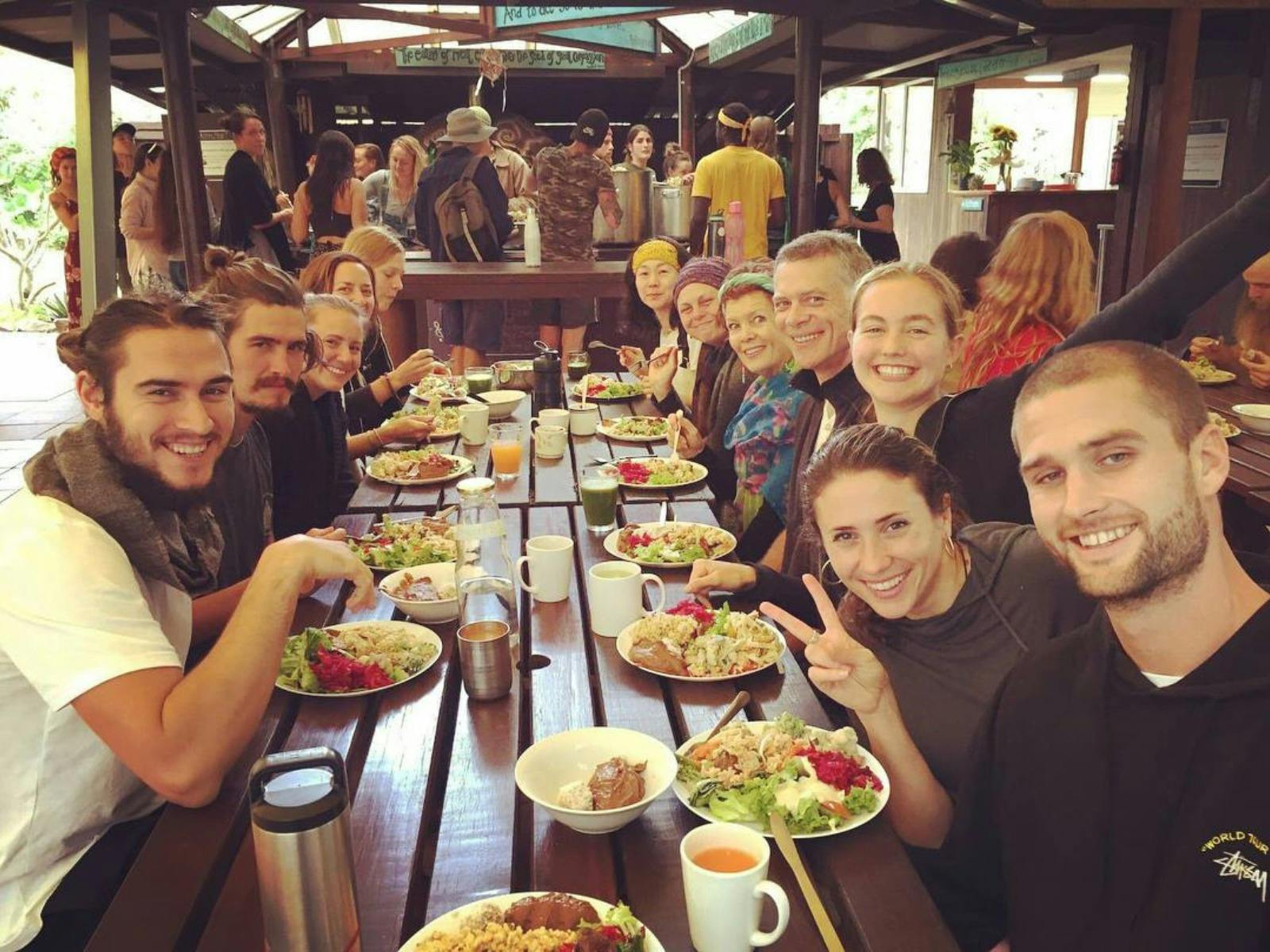A group of yogis has a yummy vegetarian lunch together. In the background people are being served