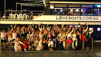 Group of people standing alongside Love Boat having a party