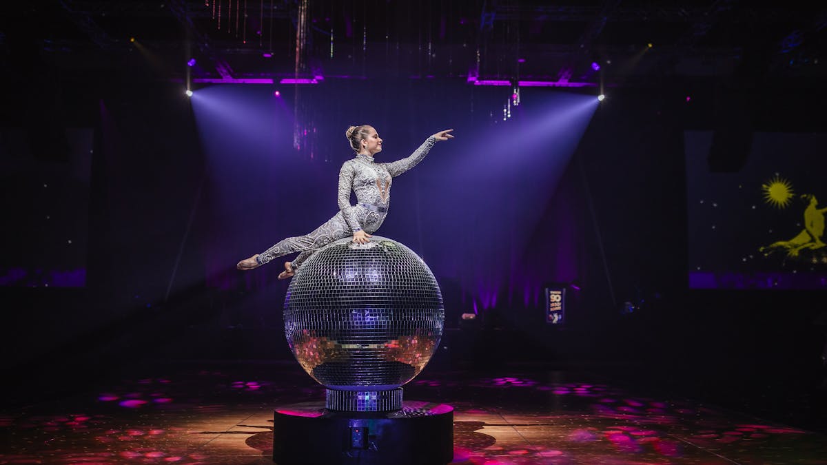 Giant Mirror Ball with performer on top posing with her arm out