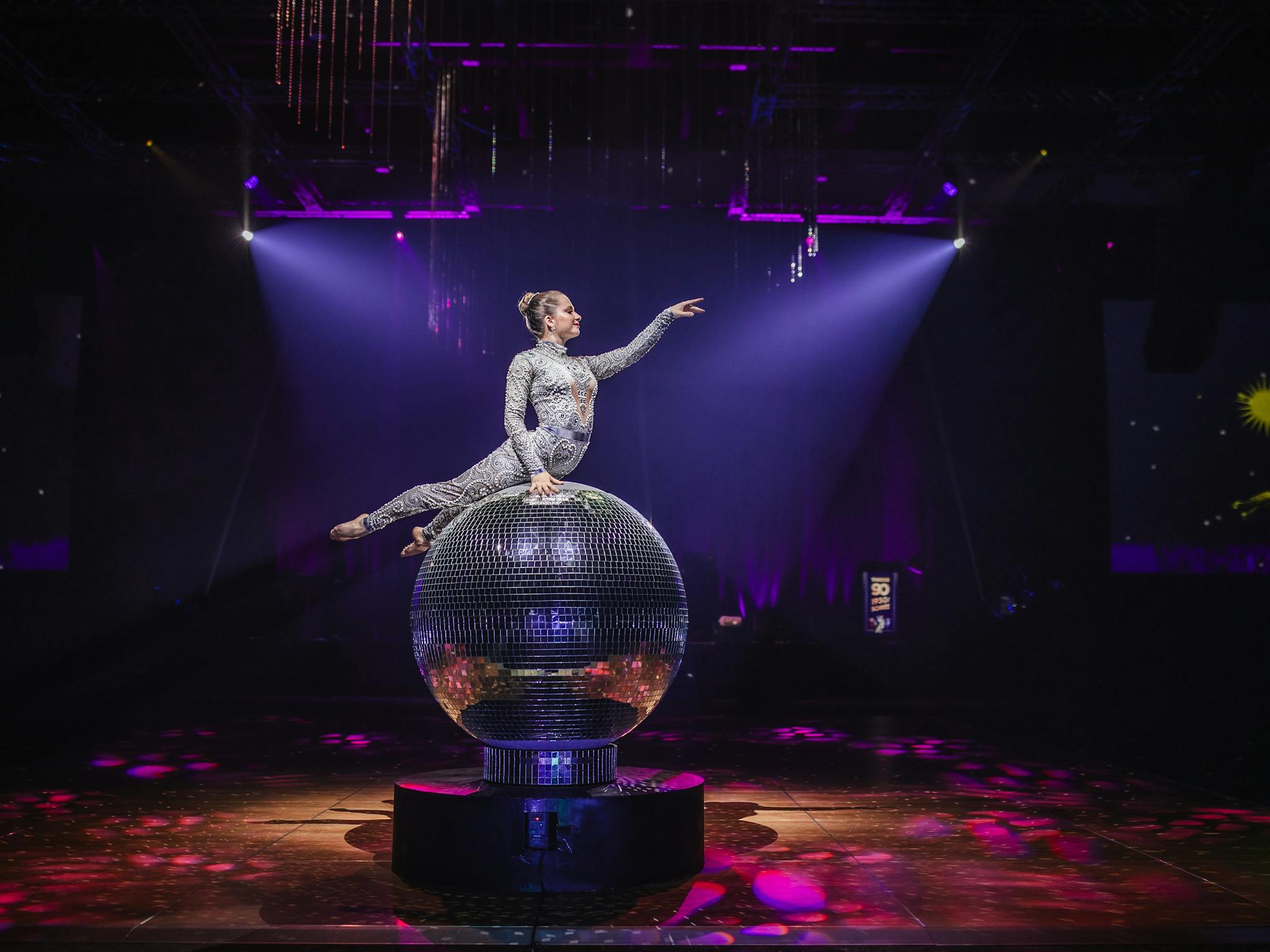 Giant Mirror Ball with performer on top posing with her arm out Giant Mirror Ball with performer on top posing with her arm out
