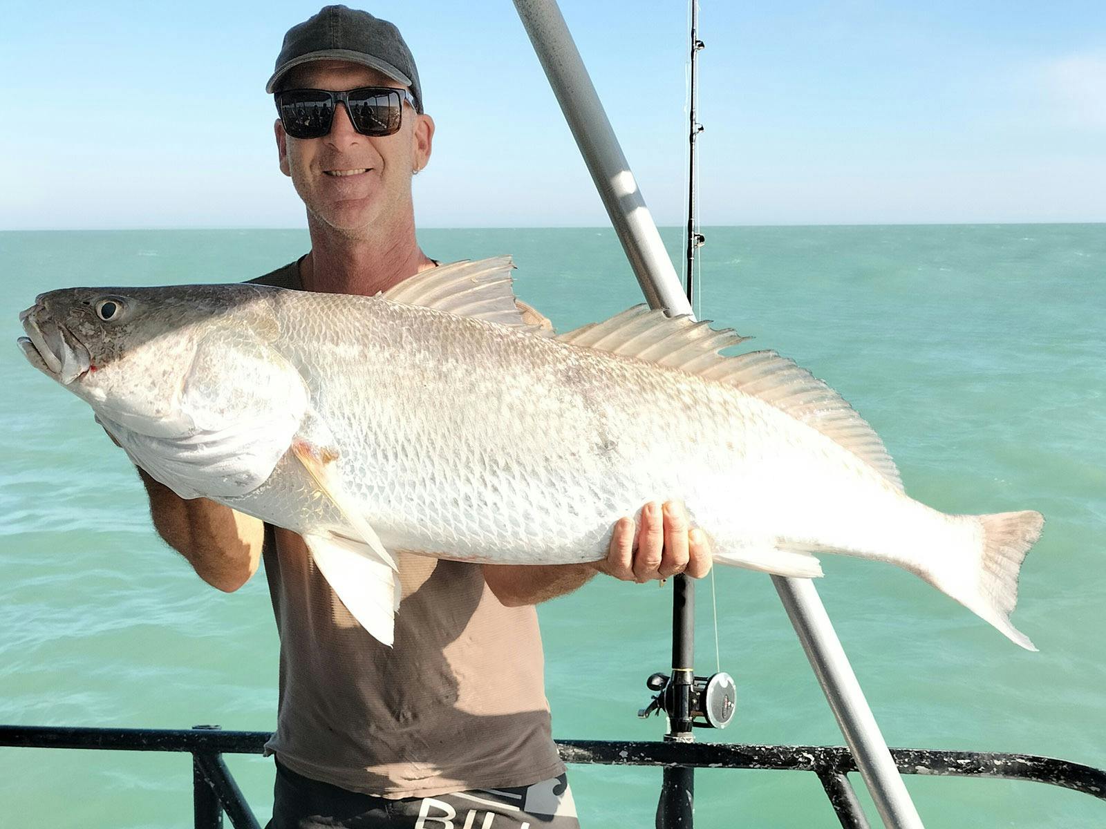 A man holding a fish on a Darwin Red Devil Charter.