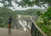 Person stands at railing of lookout high above gorge with views of waterfall.