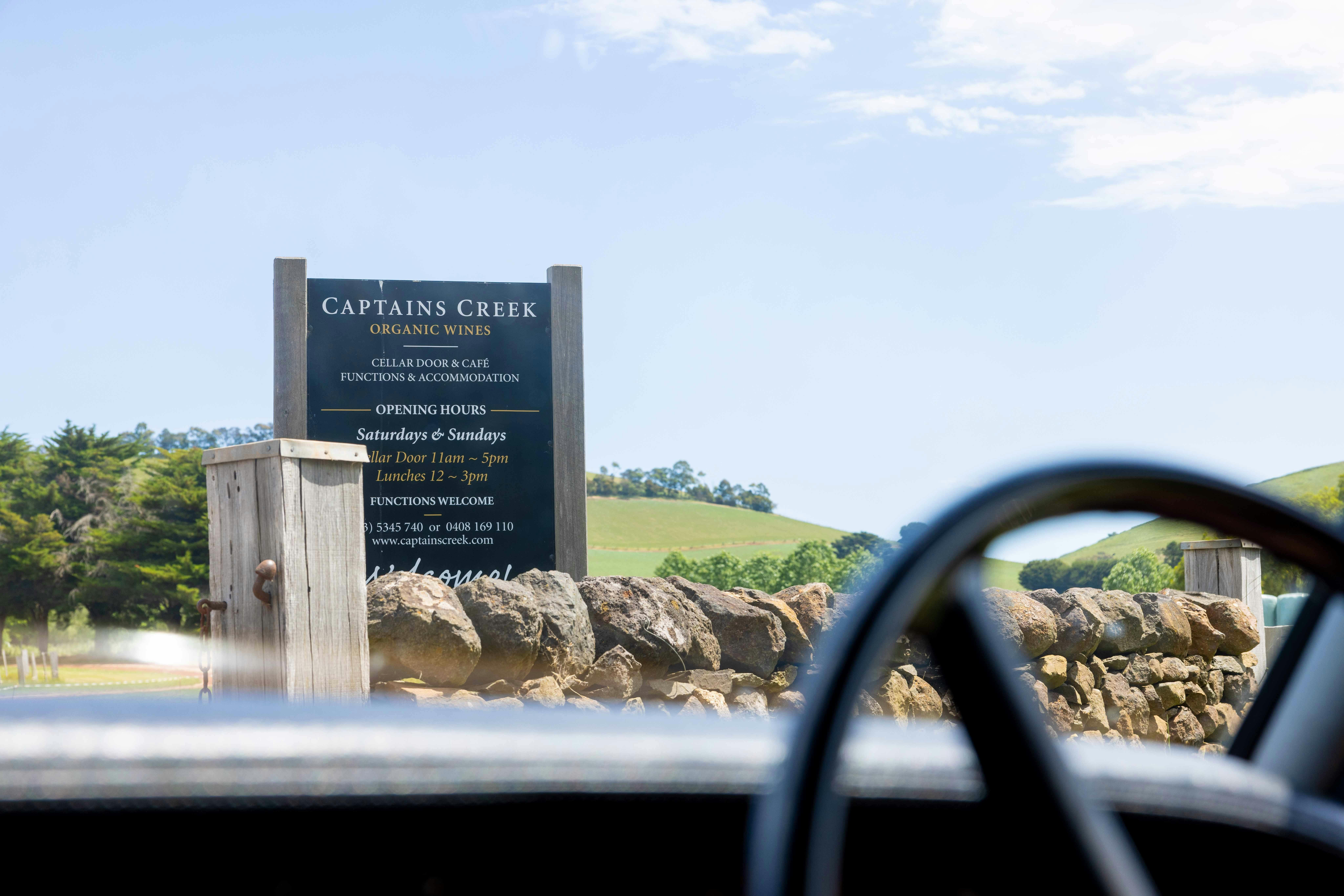 the steering wheel of the Rolls Royce in the foreground.  The Captains Creek organic wines sign.